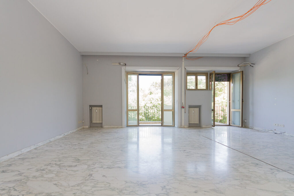 Salone luminoso con pavimento in marmo e accesso a balcone soleggiato, vendita roma flaminio proposto da Class & Country Homes.