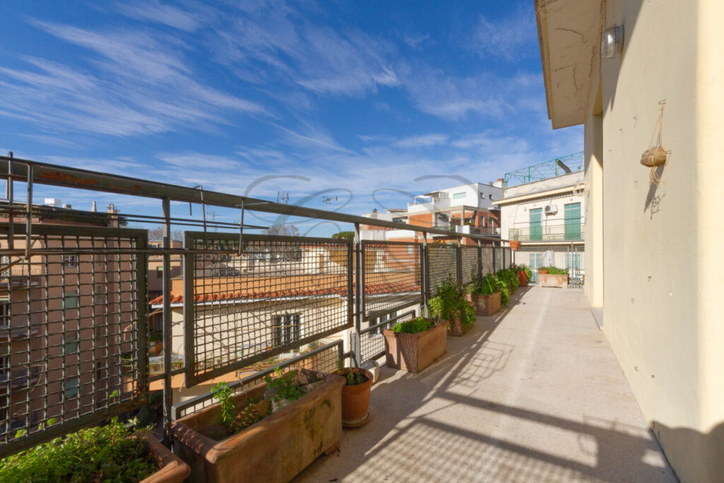 Ampia balconata abitabile dell'appartamento venduto a Monteverde Vecchio, con fioriere e vista sui palazzi circostanti in una giornata di sole.