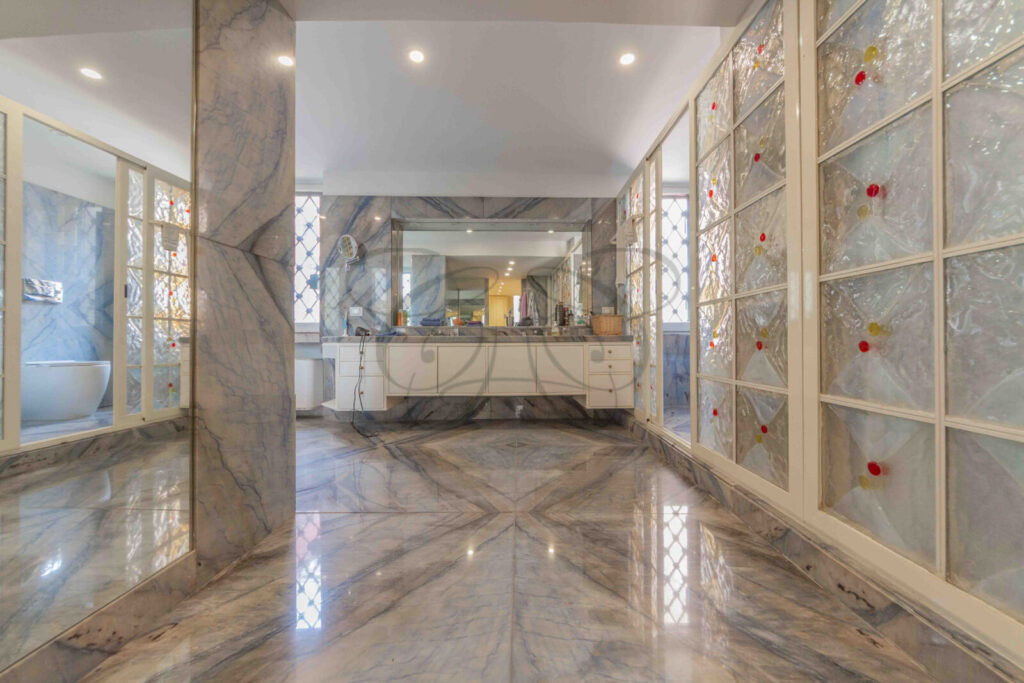 Lussuosa sala da bagno con pareti in marmo e grandi specchi in un attico in affitto a Roma.