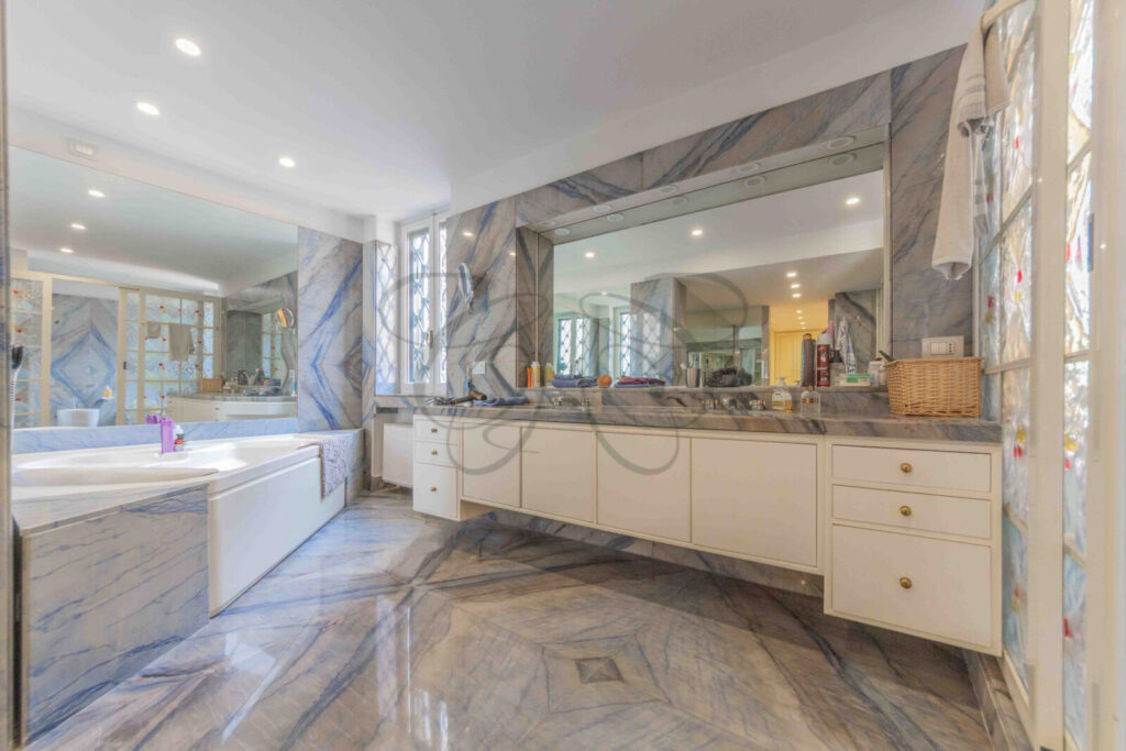 Lussuosa sala da bagno con pareti in marmo e grandi specchi in un attico in affitto a Roma.