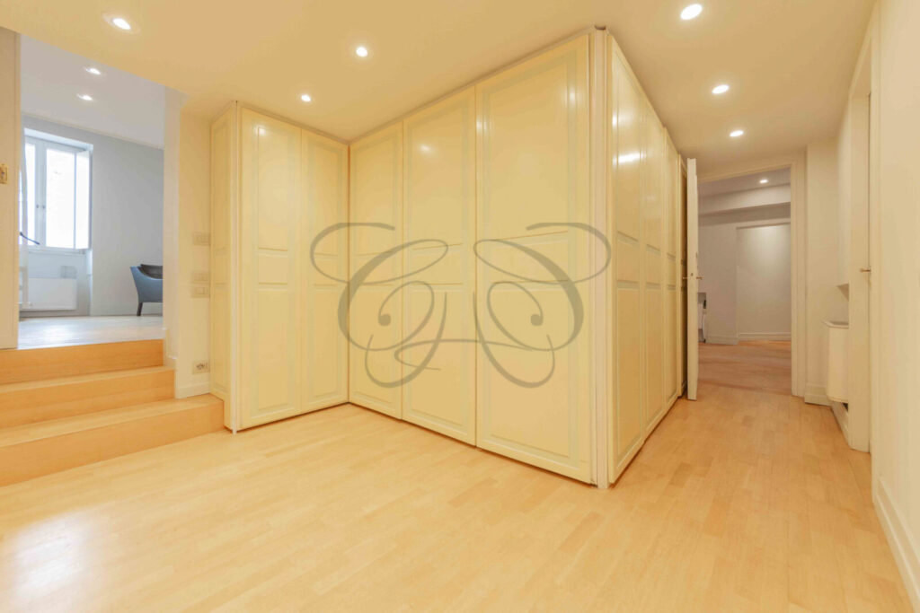 Particolare di un corridoio d'ingresso con pareti decorate con motivi ornamentali in un attico di prestigio a Roma.