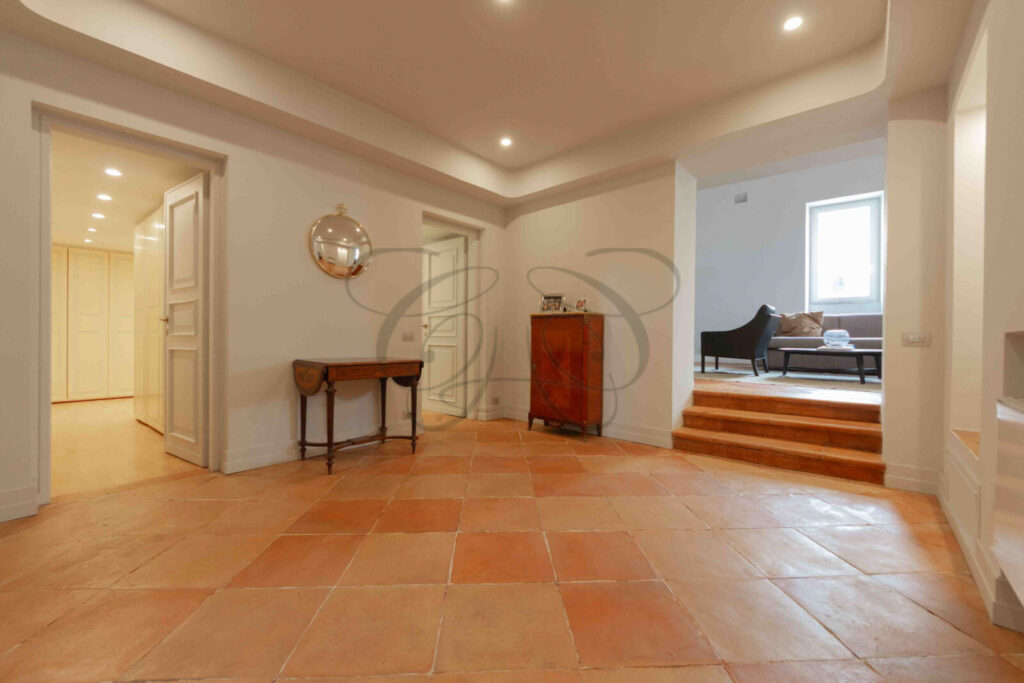 Particolare di un corridoio d'ingresso con pareti decorate con motivi ornamentali in un attico di prestigio a Roma.