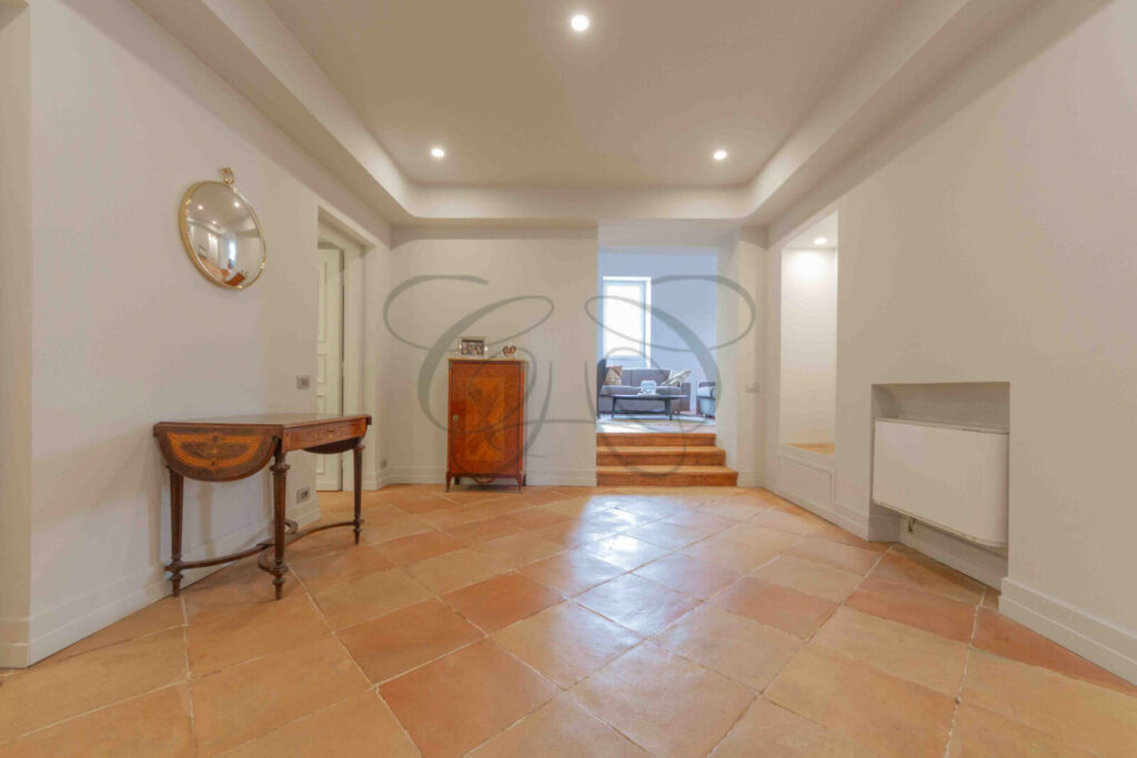 Particolare di un corridoio d'ingresso con pareti decorate con motivi ornamentali in un attico di prestigio a Roma.