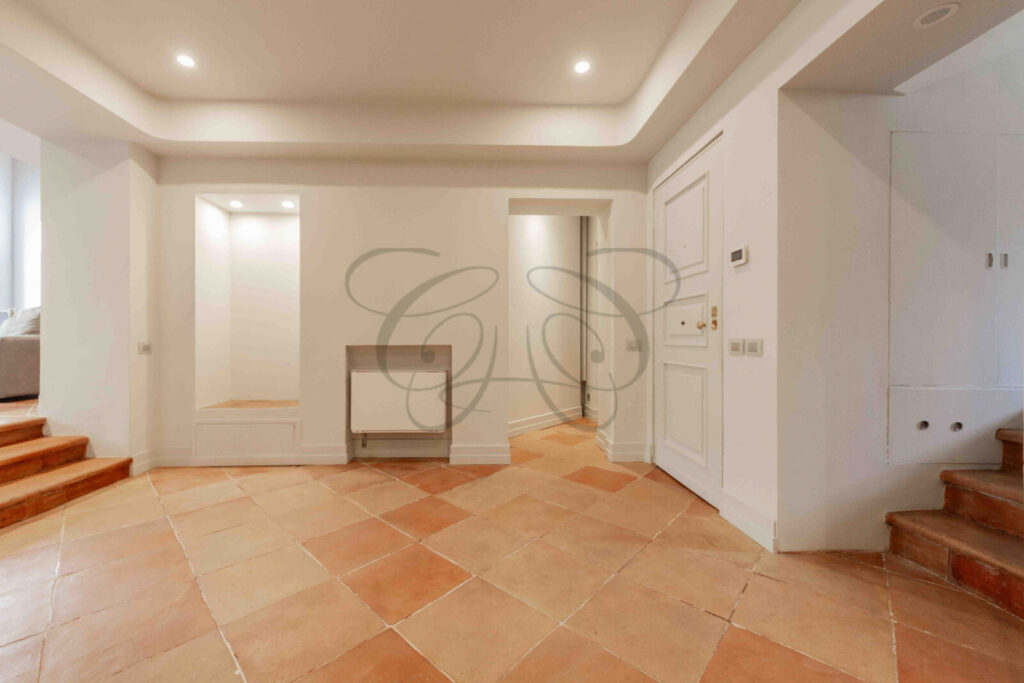 Particolare di un corridoio d'ingresso con pareti decorate con motivi ornamentali in un attico di prestigio a Roma.