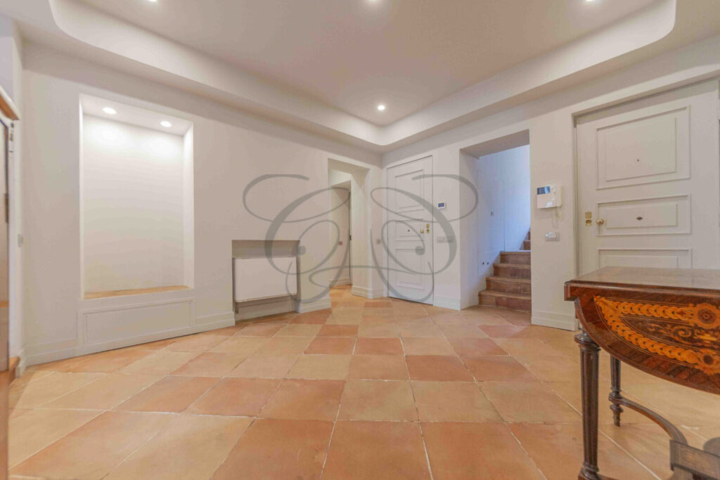 Particolare di un corridoio d'ingresso con pareti decorate con motivi ornamentali in un attico di prestigio a Roma.