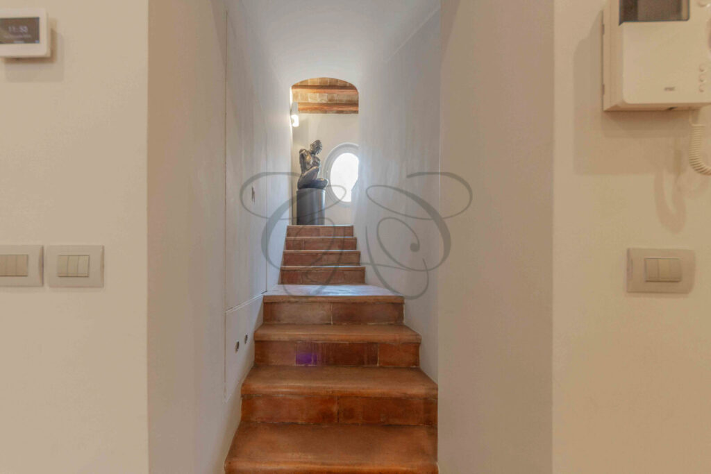 Scala di design in pietra con gradini a sbalzo e una scultura moderna posizionata alla base, in una villa di lusso.