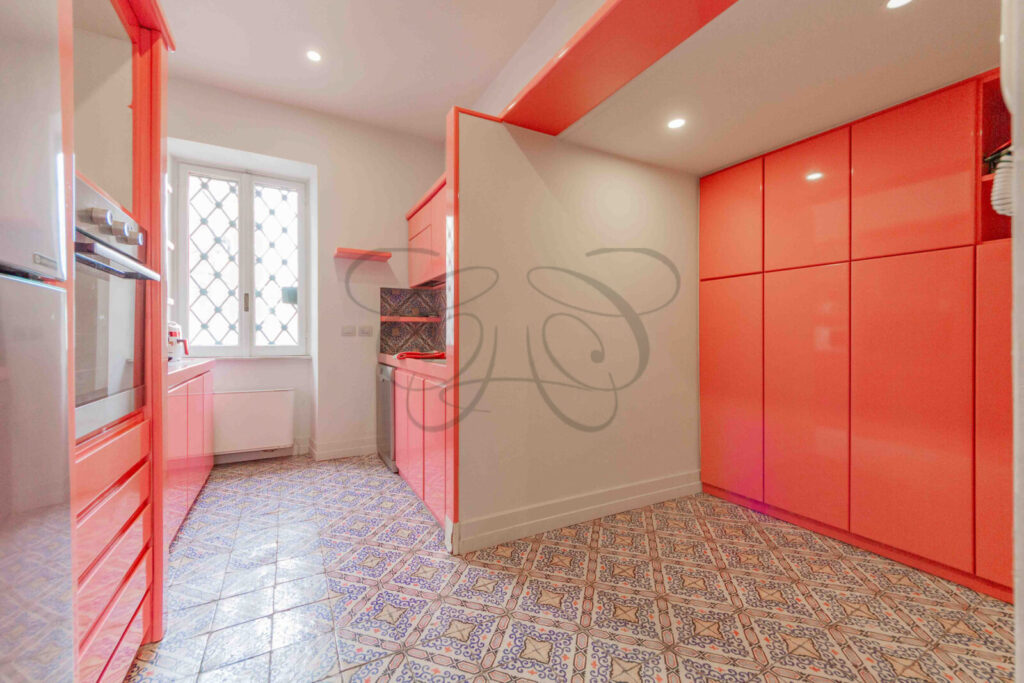 Ampia cucina di design con isola centrale colorata, sgabelli da bar ed elettrodomestici di alta gamma in un appartamento di lusso.