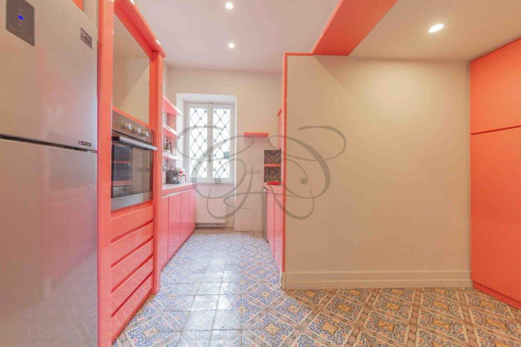 Ampia cucina di design con isola centrale colorata, sgabelli da bar ed elettrodomestici di alta gamma in un appartamento di lusso.