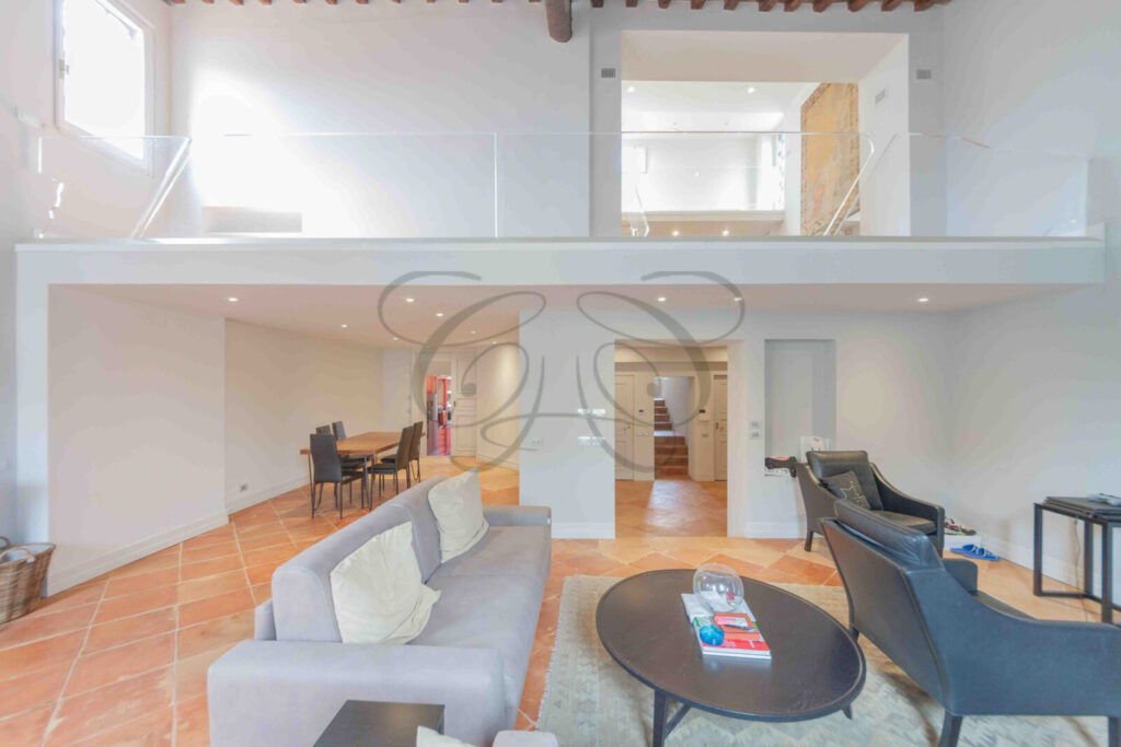 Salone di un attico di lusso a Roma con alti soffitti con travi in legno a vista e pavimento in cotto.