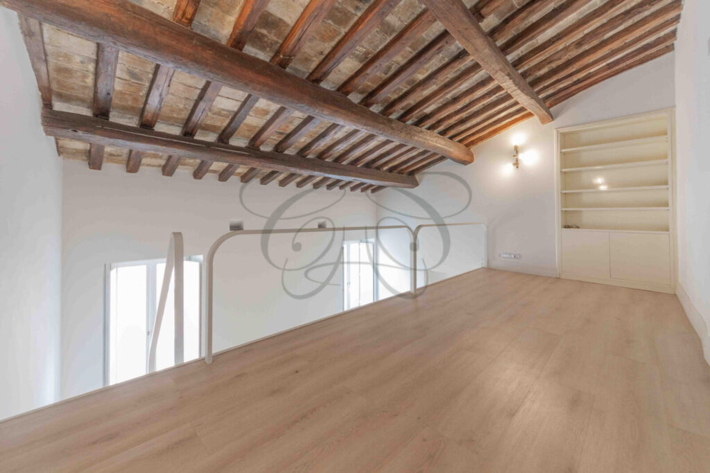 Camera da letto padronale in un attico a Roma, con soffitti con travi a vista e pavimento in parquet.