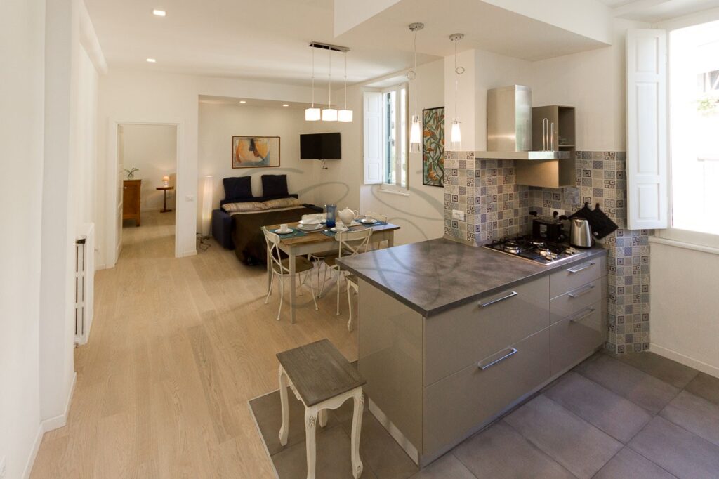 Soggiorno con cucina a vista di design in appartamento ristrutturato e affittato da Class & Country Homes a Roma, Ponte Milvio.