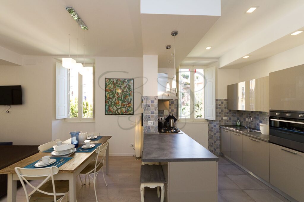 Soggiorno con cucina a vista di design in appartamento ristrutturato e affittato da Class & Country Homes a Roma, Ponte Milvio.