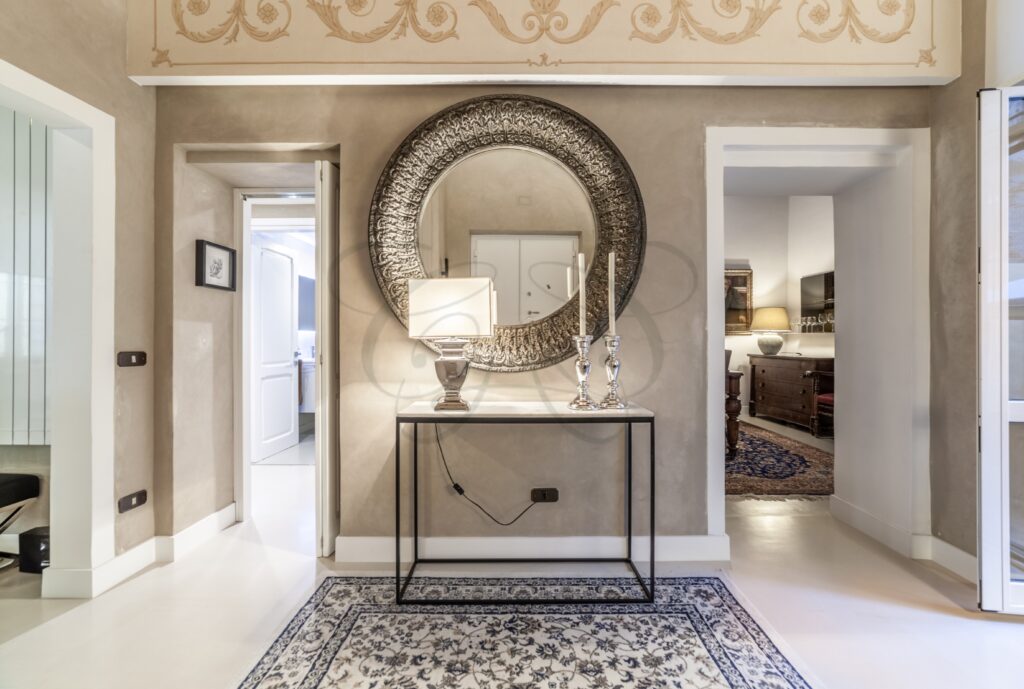 Dettaglio di una consolle con specchio, vasi e un'illuminazione soffusa.