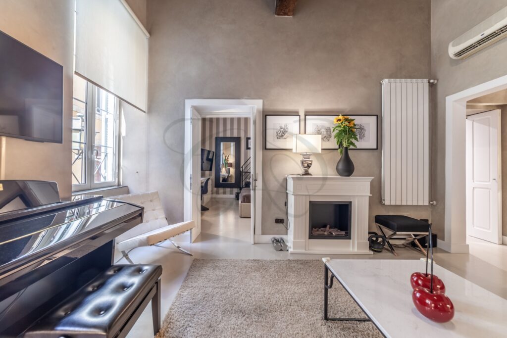 Salone di un appartamento nel centro di Roma, con camino, mobili di design e soffitto in travi di legno a vista.