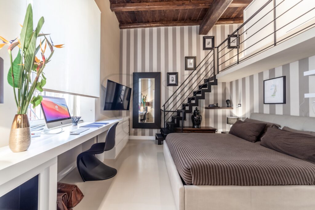 Dettaglio di una scala nera e moderna che porta al soppalco in una camera da letto.