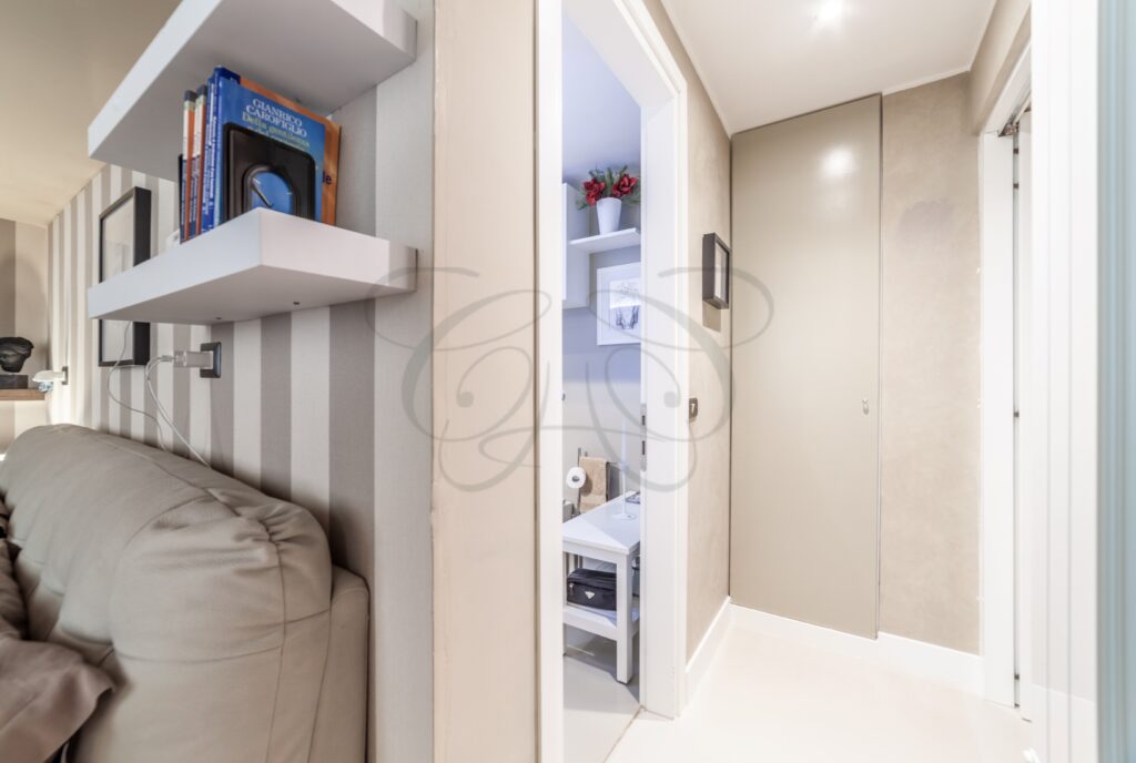 Un bagno con lavabo, rubinetto e pareti rivestite in marmo bianco, che riflettono la luce.