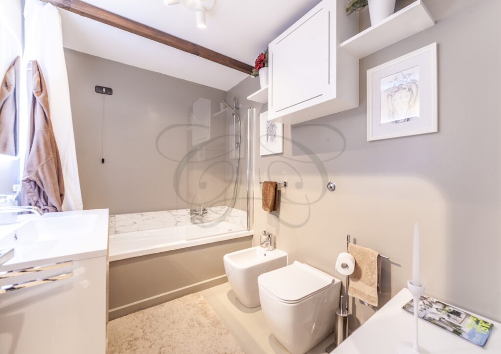 Bagno principale con vasca, lavabo e pareti in marmo.