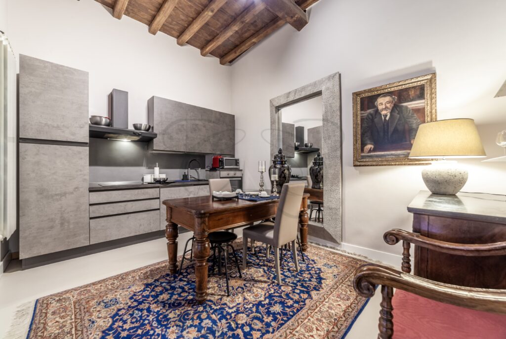 Cucina moderna con mobili grigi, pavimento a spina e un grande tavolo da pranzo al centro.