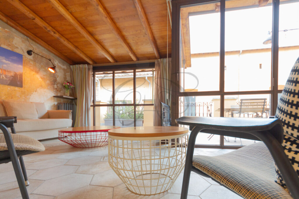 Soggiorno in una veranda luminosa con camino, in attico di lusso affittato da Class & Country Homes a Roma.