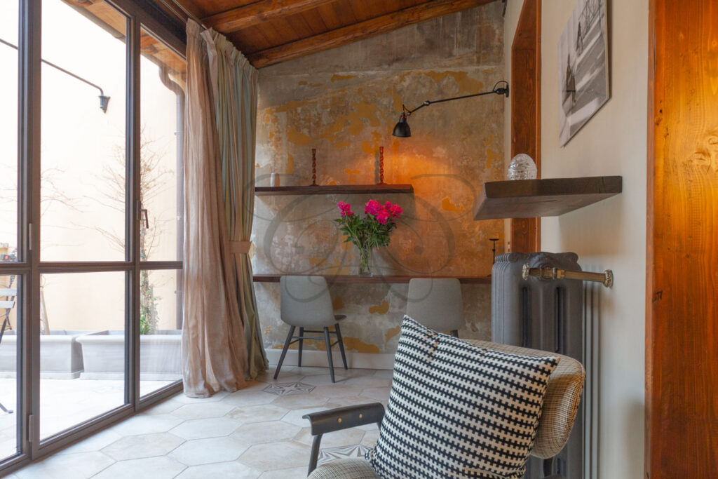 Soggiorno in una veranda luminosa con camino, in attico di lusso affittato da Class & Country Homes a Roma.