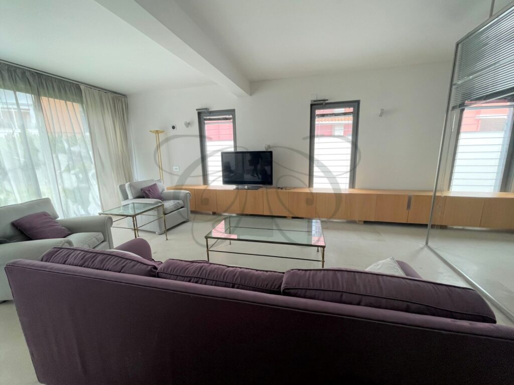 The vast double living room of a designer villa for sale in Rome, looking out onto the garden.