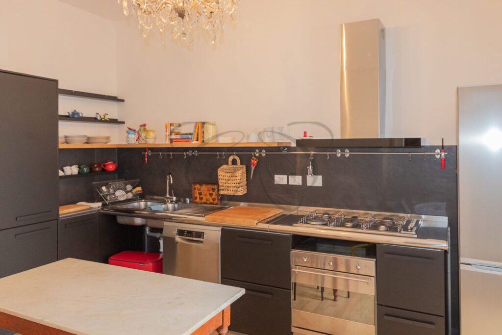 Un'altra vista della cucina con il piano cottura, il lavello e gli armadietti a muro, che ottimizzano lo spazio.