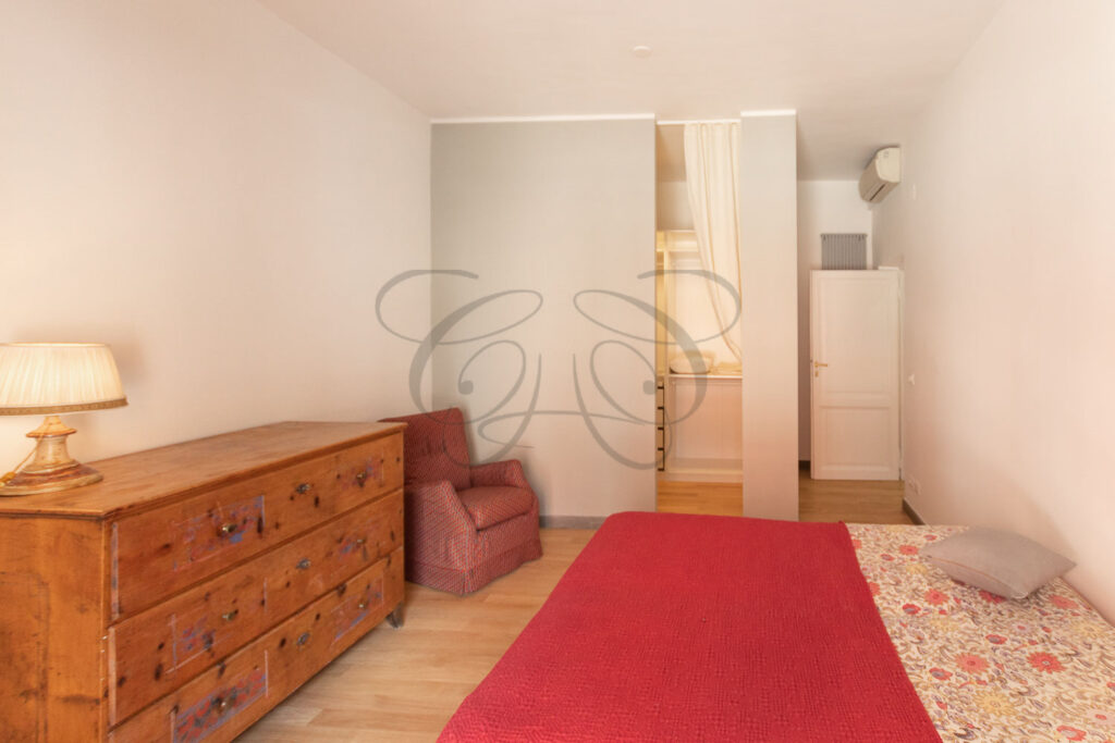 Una camera da letto con letto matrimoniale, armadi a muro e una sedia rossa.