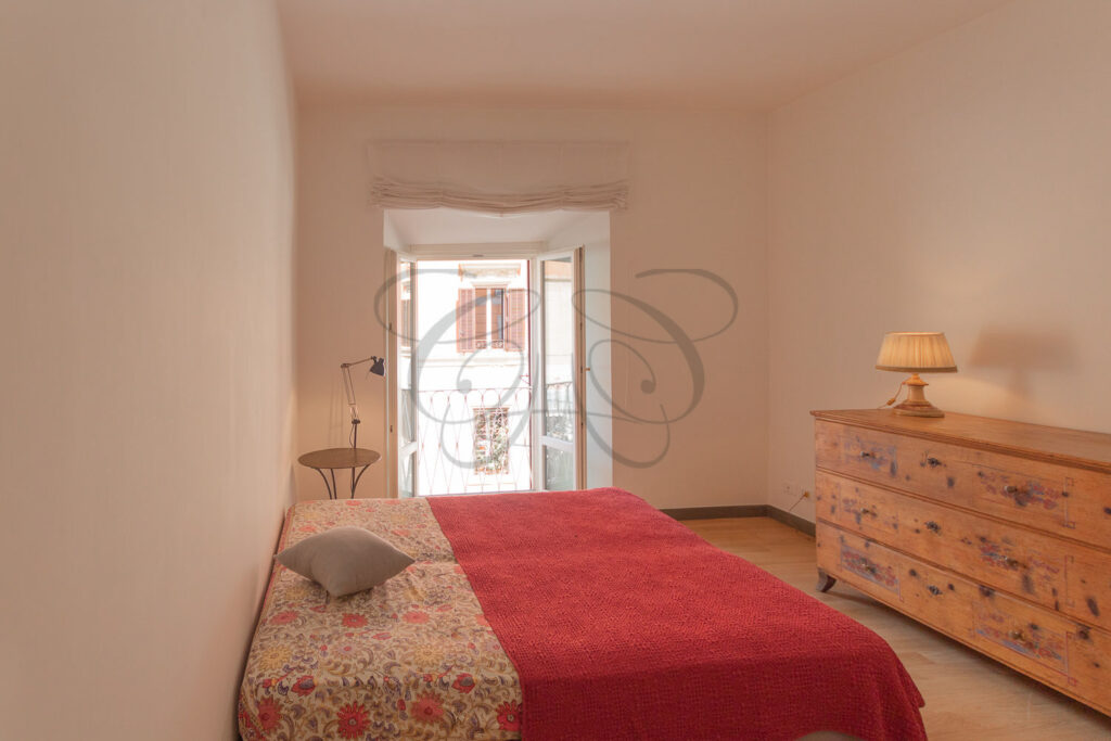 Un'altra vista della camera da letto con letto matrimoniale e una sedia rossa.