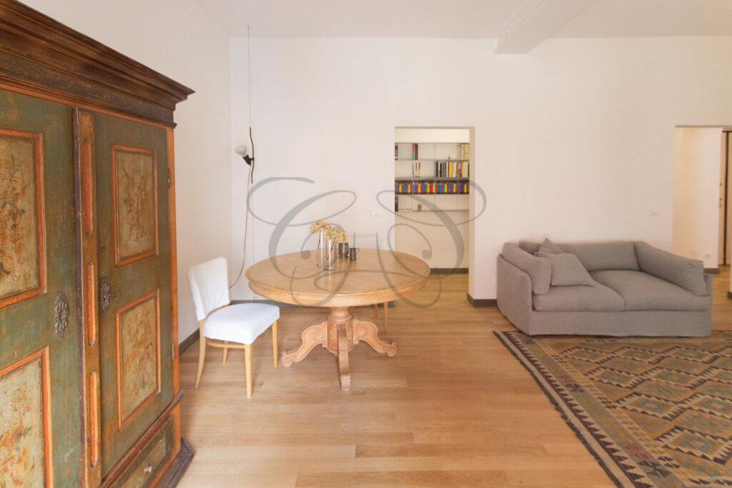 Dettaglio di una sedia di design, un tavolo e un grande mobile in legno scuro, che confermano lo stile ricercato.