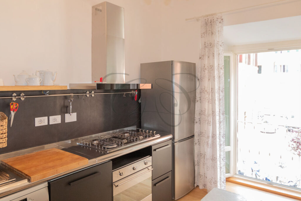Cucina abitabile con elettrodomestici hi-end in acciaio inossidabile e un piano cottura a vista.