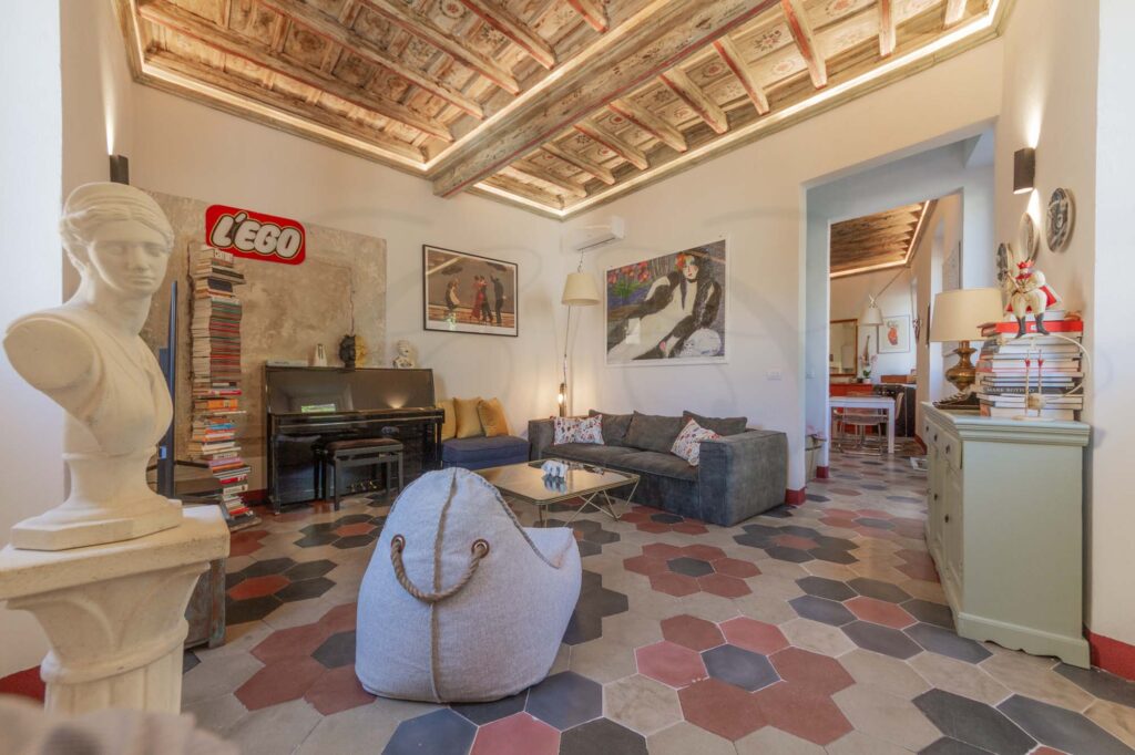 Vista panoramica sul salotto e la cucina dell'appartamento a Trastevere. Un connubio di stile e eleganza in un ambiente accogliente e raffinato. Dettagli affascinanti si fondono con un tocco moderno, creando un'atmosfera unica e invitante. Un luogo incantevole per vivere momenti indimenticabili nel cuore autentico di Roma.