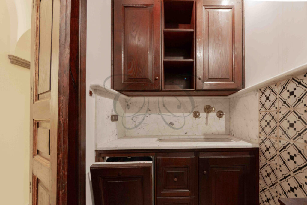 Una cucina compatta con superfici in marmo, elettrodomestici moderni e mobili in legno.