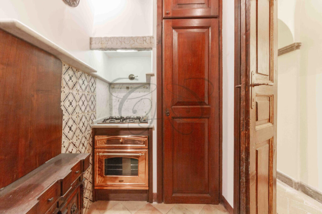 Una cucina compatta con superfici in marmo, elettrodomestici moderni e mobili in legno.