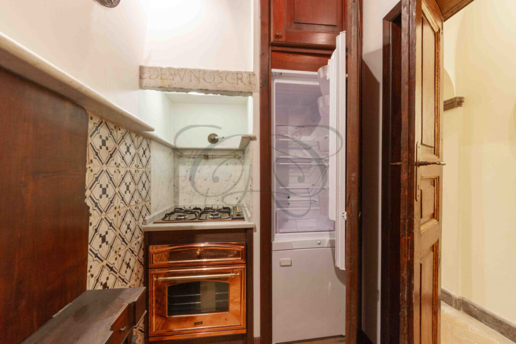 Una cucina compatta con superfici in marmo, elettrodomestici moderni e mobili in legno.