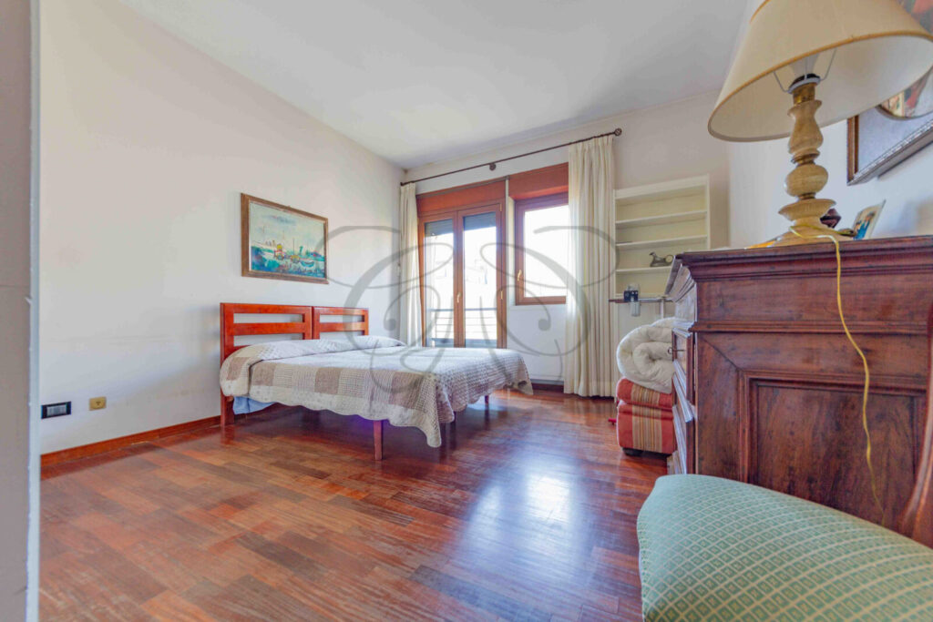 Seconda camera da letto con un letto singolo, pavimento in parquet e una finestra con vista.
