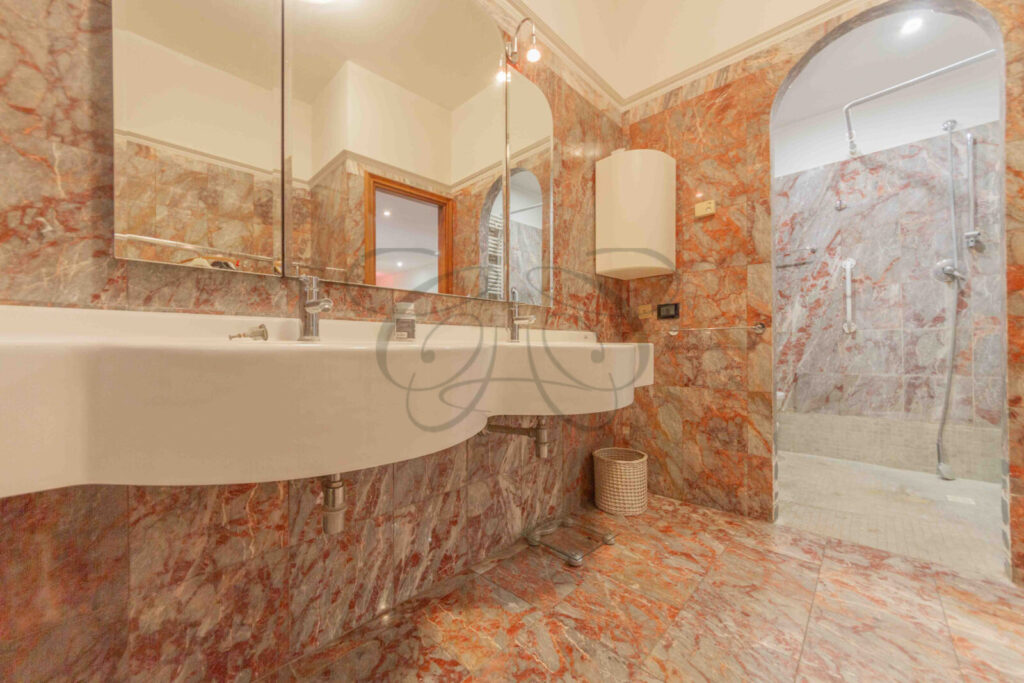 Bagno con un doppio lavabo, specchio grande e finiture in pietra e piastrelle.
