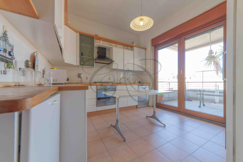 La cucina con mobili in stile classico di colore verde, con piano di lavoro e finestra.