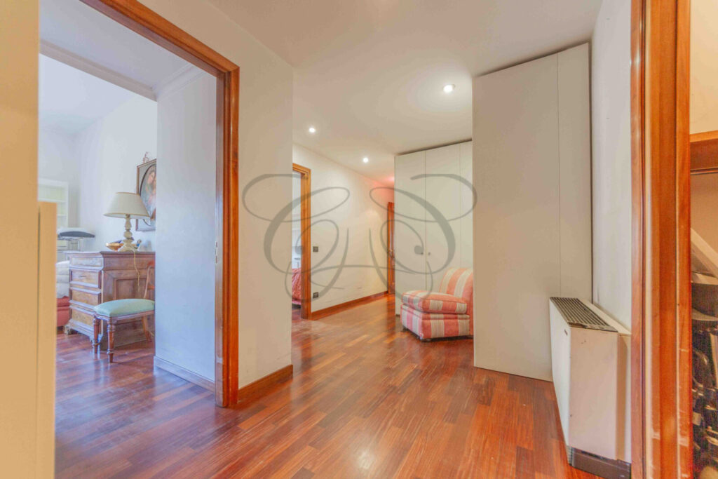 Corridoio con pavimento in parquet che porta alla zona notte, con un'illuminazione soffusa.