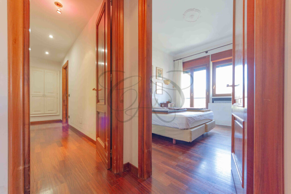 Ampia camera da letto con un letto matrimoniale, pavimento in parquet e un'apertura che conduce alla cabina armadio.