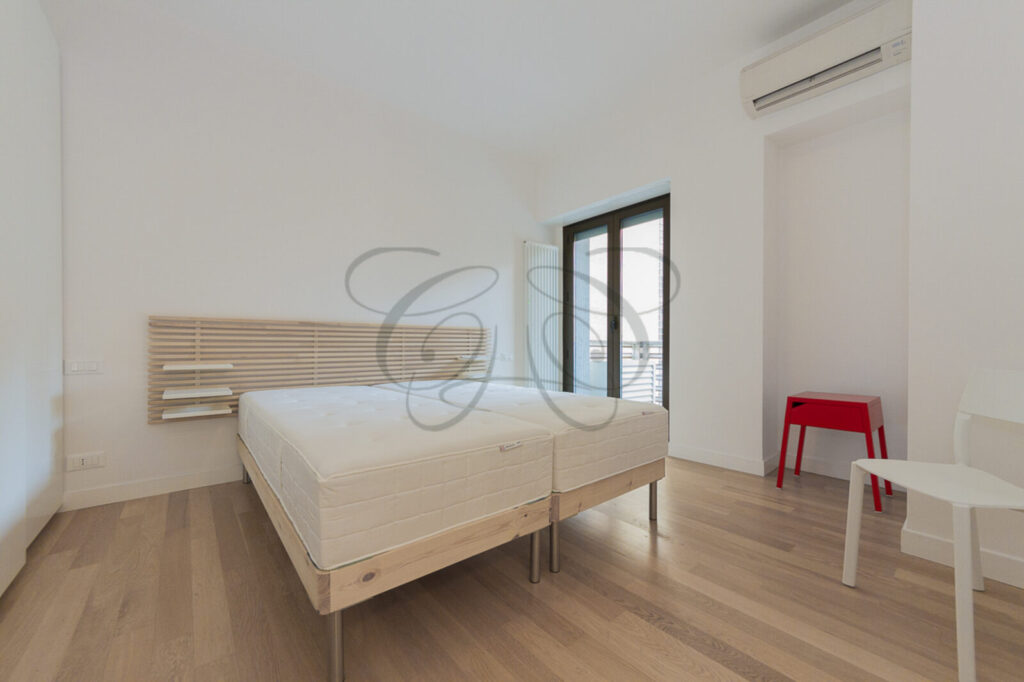 Camera da letto con design minimalista in appartamento moderno affittato da Class & Country Homes a Roma Ostiense.