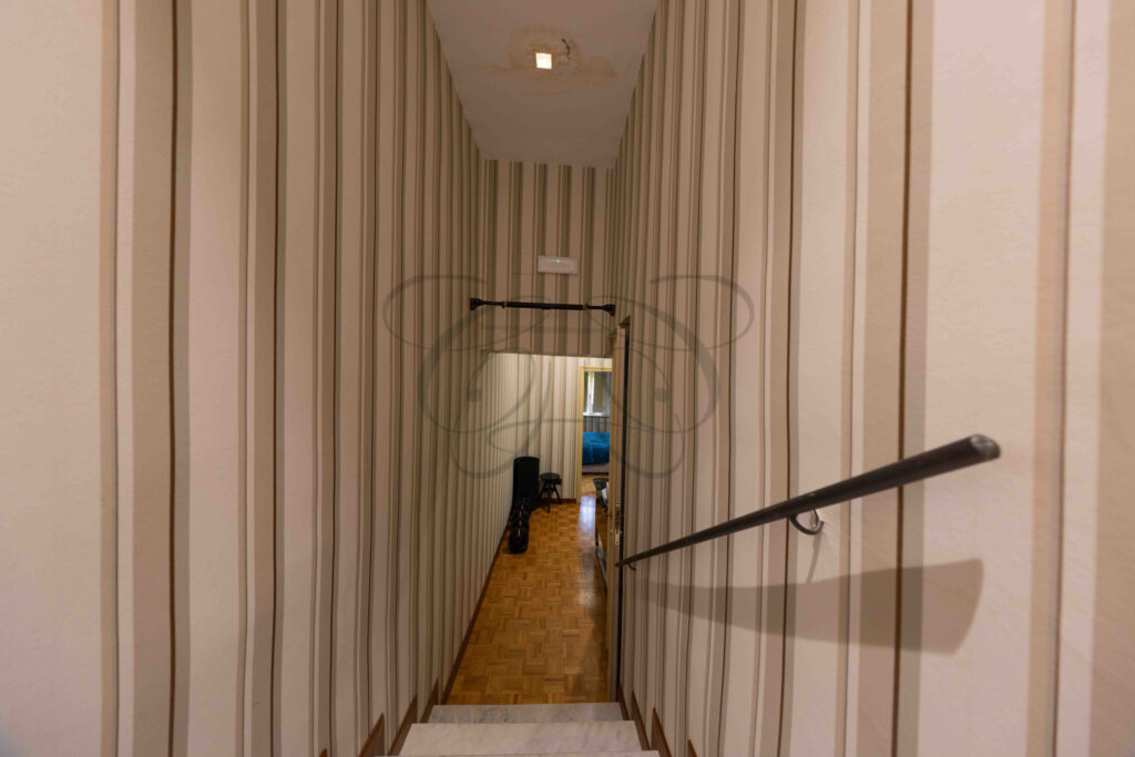 Internal staircase with handrail and striped wallpaper, penthouse for rent Rome historic center.