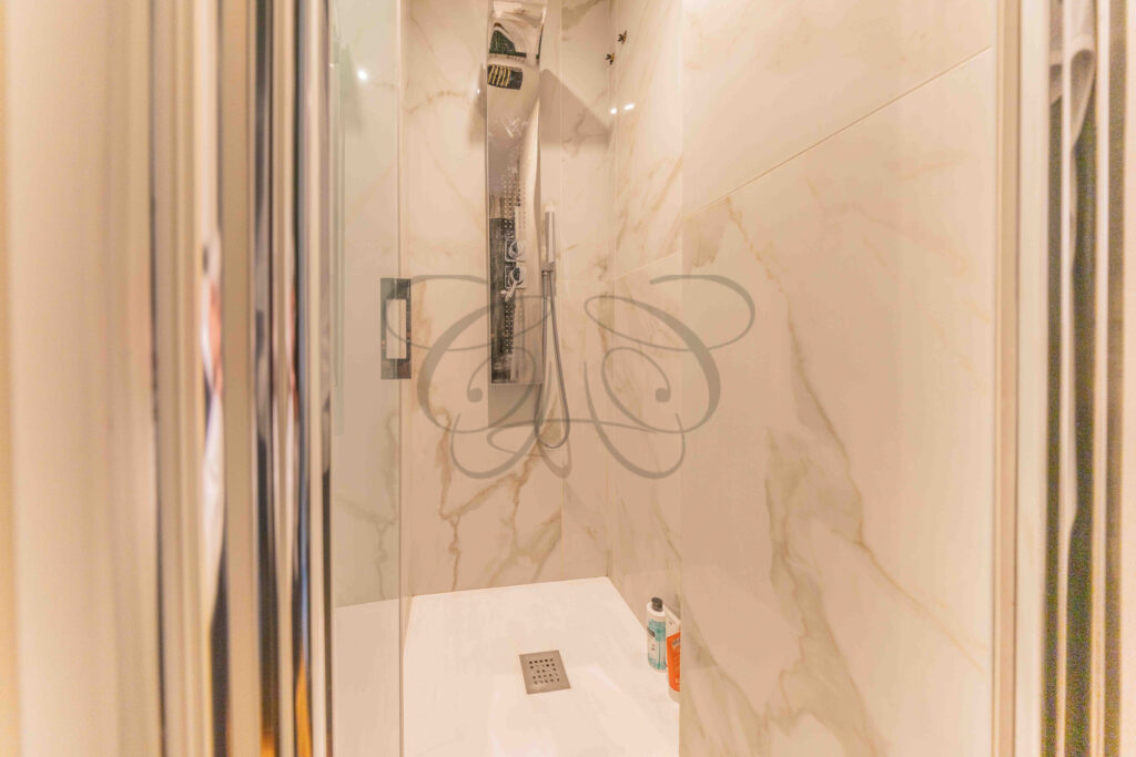 Modern shower cabin with marble cladding and equipped shower column, penthouse bathroom for rent Rome.