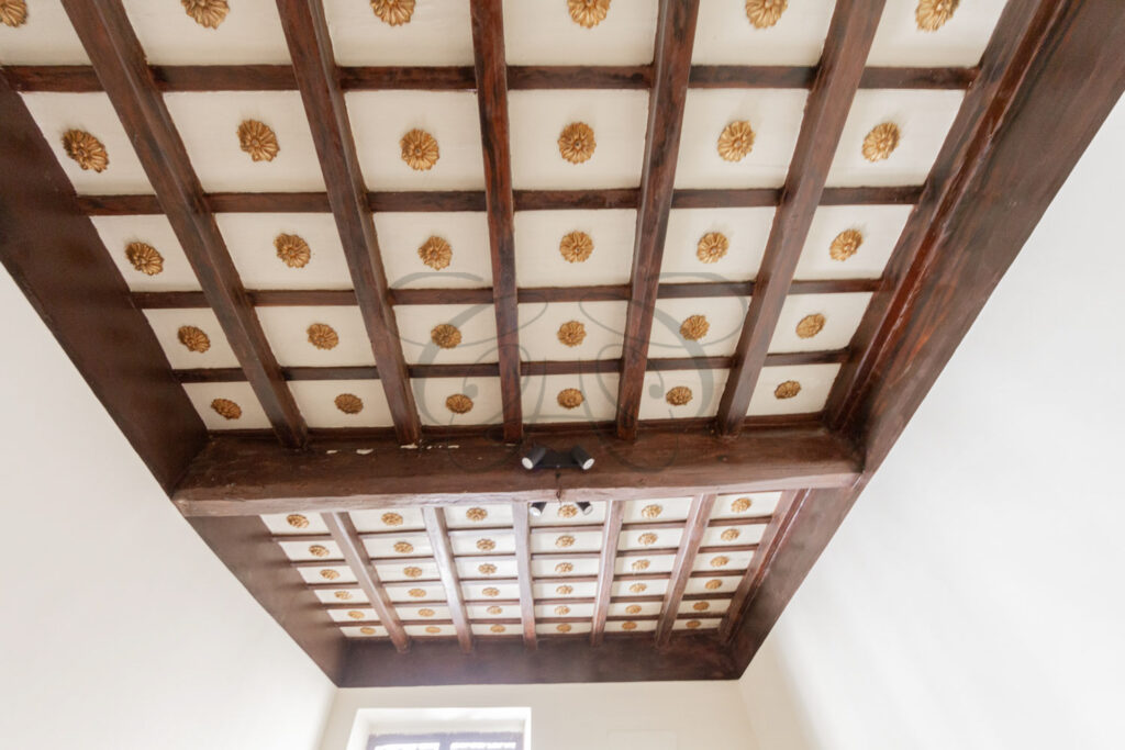 Antique wooden coffered ceiling with gilded rosettes, detail of penthouse for rent Rome center.