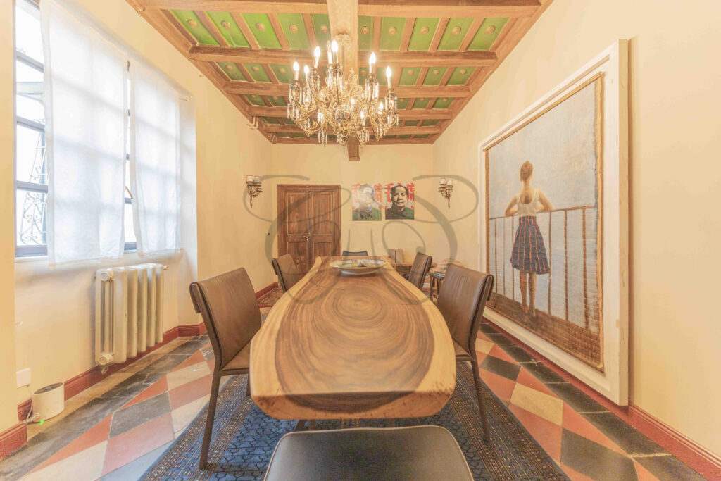 Elegant dining room with solid wood table, coffered ceiling, and large painting, penthouse for rent Rome.