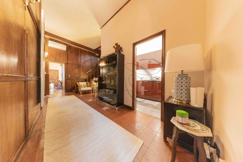 Hallway with wood paneling, terracotta floor, and access to the kitchen, penthouse for rent Rome center.