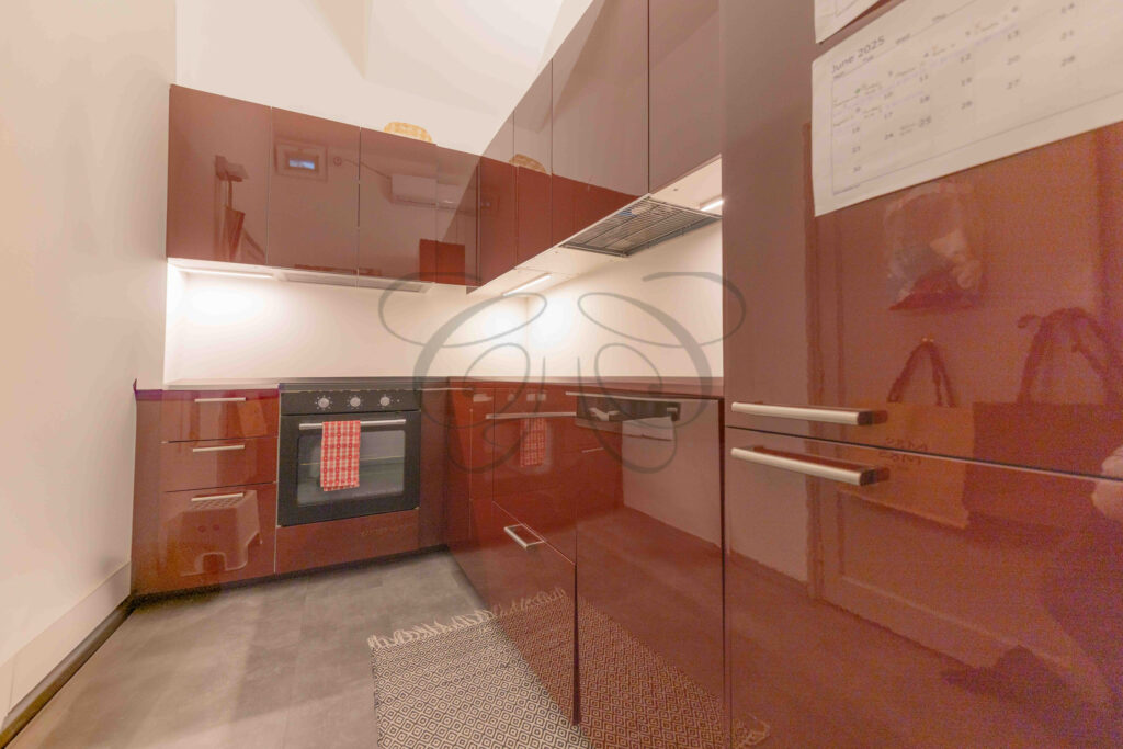 Modern kitchen with dark red lacquered cabinets and integrated appliances, penthouse for rent Rome.