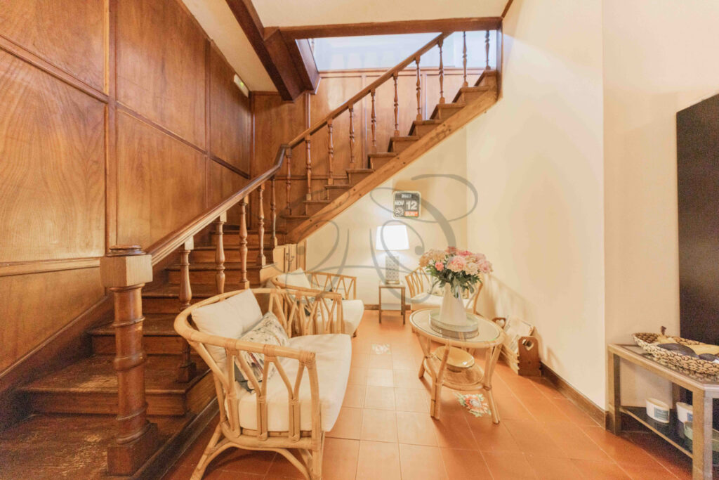 Internal wooden staircase and relaxing nook with wicker armchairs, penthouse for rent Rome historic center.