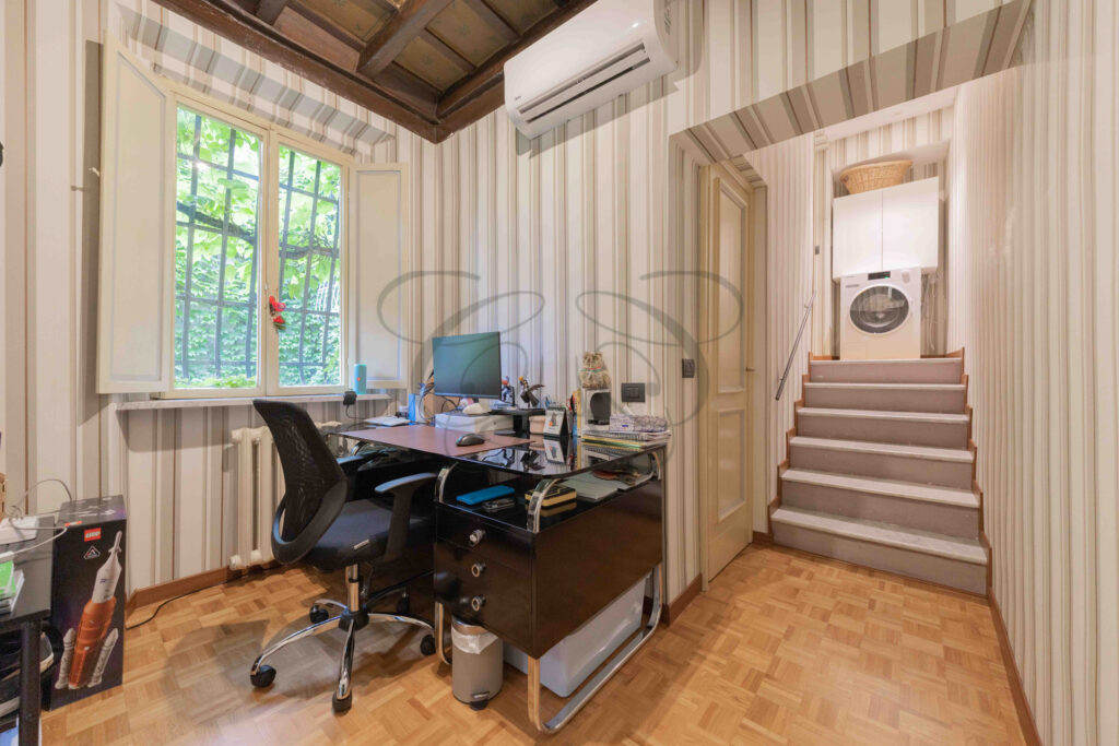 Study with desk, window, and coffered ceiling, penthouse for rent Rome center. Laundry machine visible on mezzanine.