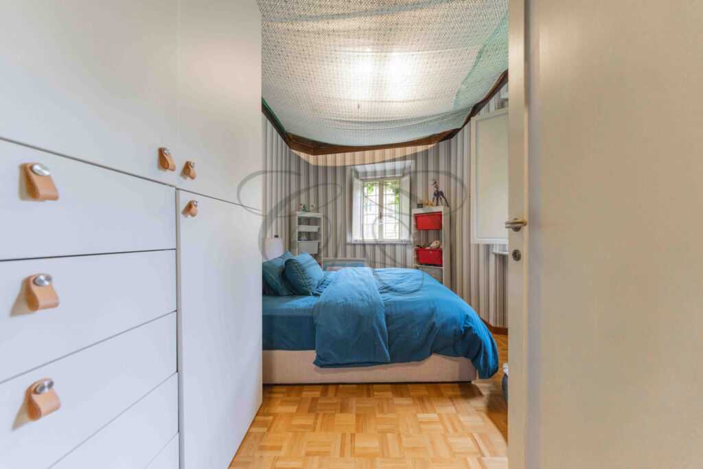 Bedroom with white wardrobe, bed with blue linen, and net canopy, penthouse for rent Rome.