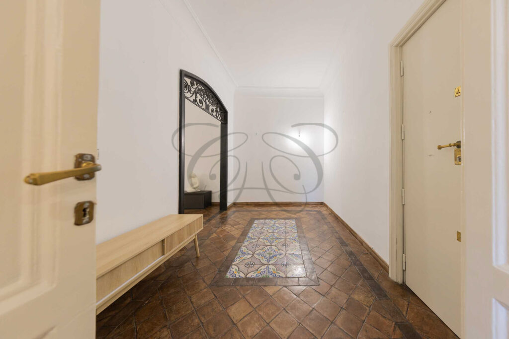 Ingresso di appartamento nel Rione Monti con specchio, pianta, poltrone gialle e pavimento in cotto.